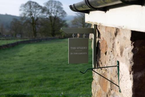 a sign on a building with a field in the background at Hill End Cottages in Warslow