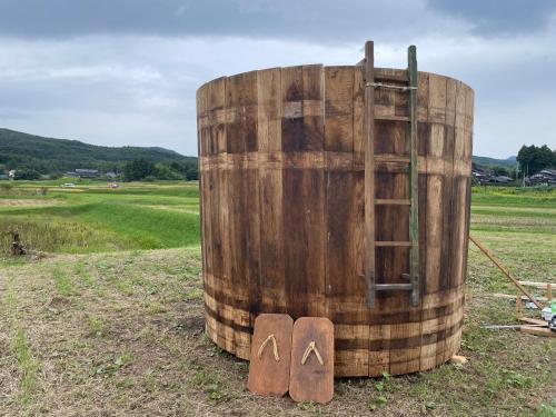 a large wooden barrel sitting in a field at temple stay 玉林寺 in Sado