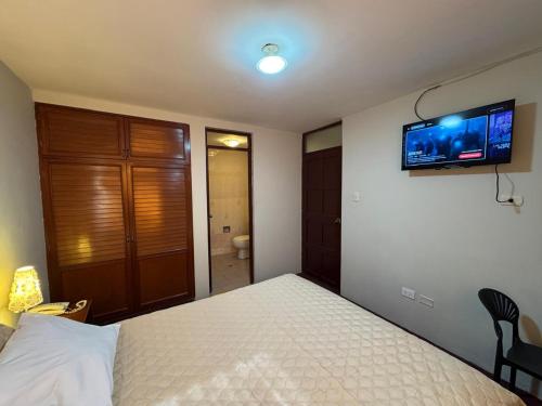 a bedroom with a bed and a television on the wall at Hotel Los Angeles in Arequipa