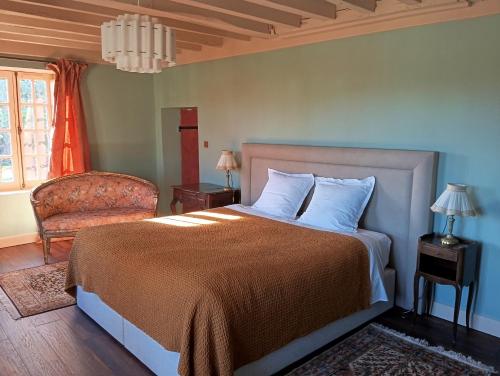 a bedroom with a bed and a chair and a window at D OR et D ARGENT in Arceau