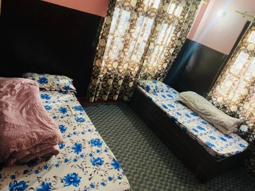 een slaapkamer met twee bedden met blauwe bloemen bij Pur guest house in Kathmandu