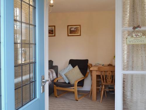 a door leading into a room with a chair and a table at Forest View in Peak Forest