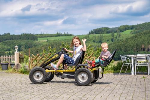 two children are riding on a toy car at Ferienhof Rüßmann in Lennestadt