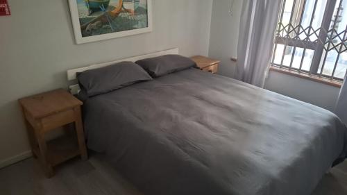 a bedroom with a large bed with a wooden table at Sea Cottage 49 in Mossel Bay