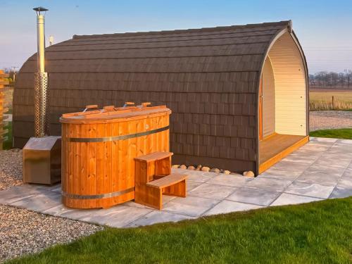a small shed with a bench next to a wooden barrel at Coo Pod-Uk45324 in Forfar