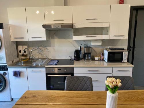 een keuken met witte kasten en een houten tafel bij The Country Stop Apartment in Łęki