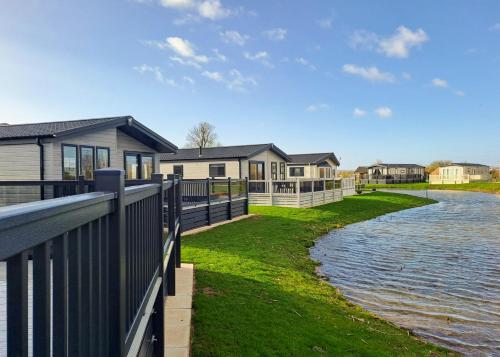 a house with a fence next to a body of water at Helsey Farm Cottages in Helsey