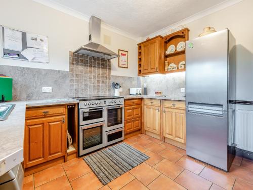 a kitchen with wooden cabinets and stainless steel appliances at Halls Bank Farm in Aspatria