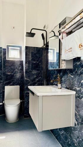 a bathroom with a white sink and a toilet at Gành Đá Đĩa Retreat Hotel in Tuy An