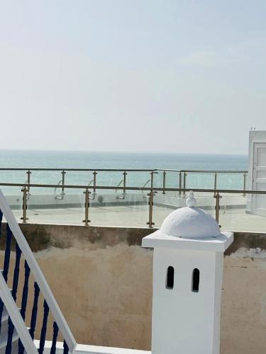 a white building on a balcony with the ocean in the background at Riad Mazal Mogador in Essaouira