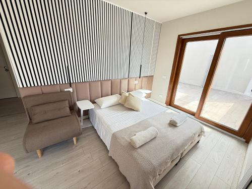 Un dormitorio con una cama y una silla y una ventana. en La Suite N4 exclusive rooms, en Alghero