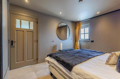 a bedroom with a large bed and a mirror at Luxe B&B Het Rijgebint in Molenaarsgraaf