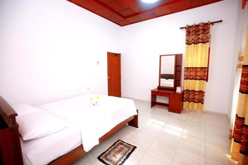 a bedroom with a white bed and a mirror at Aetos Wellness - Tangalle in Tangalle