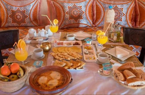 - une table avec un buffet de nourriture et de jus d'orange dans l'établissement Melody Desert Camp Merzouga, à Merzouga