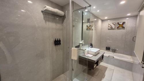 a bathroom with a shower and a sink and a tub at Ramada Ajmer in Kishangarh