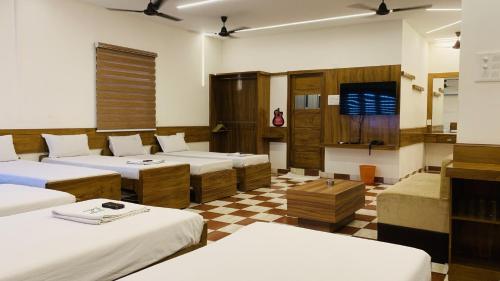 a room with beds and a tv and a checkered floor at Hotel National Tourist Home in Trichūr