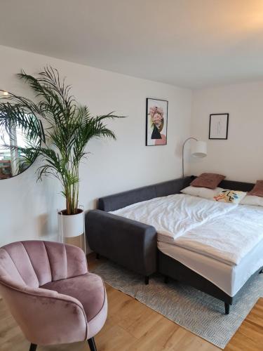 a bedroom with a bed and a chair and a plant at Zentrumsnah und modern mit Seeblick in Weggis in Weggis