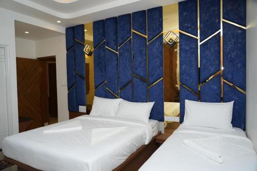 two beds in a room with a blue and gold wall at SN Comforts in Bengaluru