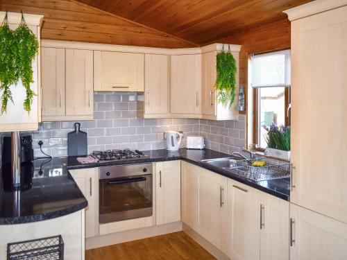 eine Küche mit weißen Schränken und schwarzen Arbeitsplatten in der Unterkunft The Dragons Den in Ilfracombe