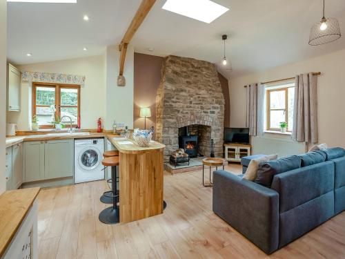 a kitchen and living room with a stone fireplace at Thornycroft Cottage in Llanvair Discoed