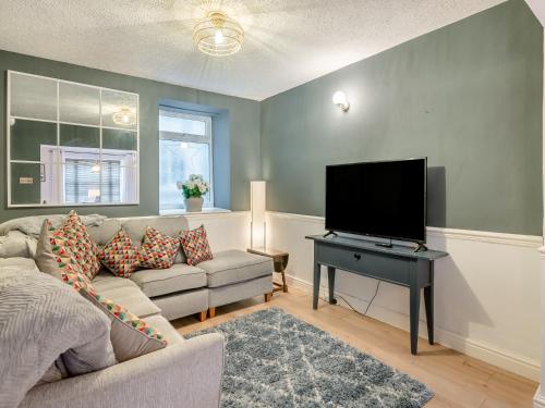 a living room with a couch and a flat screen tv at Warrington House-Uk48465 in Thornton Dale