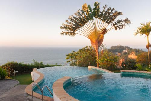 モロ・デ・サンパウロにあるMAR DÁ LIBERDADE com Postal do Farolのヤシの木と海のスイミングプール