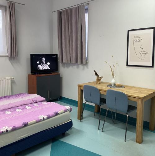 a bedroom with a table and a bed and a television at Hostel Iveda in Świebodzin