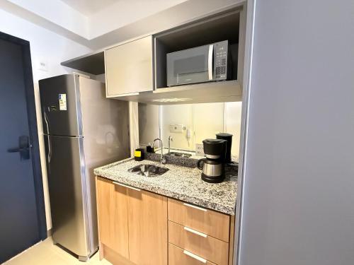 a kitchen with a sink and a microwave at On Jurupis in Sao Paulo