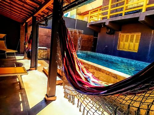 a hammock in a room with a swimming pool at PANORÂMIC LUXO EXCLUSIVe in Santa Cruz Cabrália