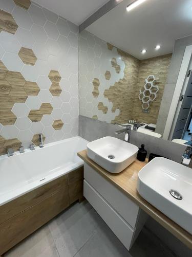 a bathroom with a sink and a tub and a sink and a mirror at 3 Rooms Apartment in Gdańsk