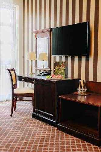 a hotel room with a desk with a television on the wall at Hotel Wileński in Olsztyn