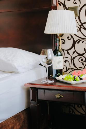 a table with a glass of wine and a plate of food at Hotel Wileński in Olsztyn