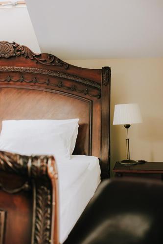 a bed with a wooden headboard and a table with a lamp at Hotel Wileński in Olsztyn