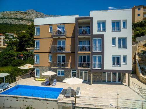 an apartment building with a swimming pool and umbrellas at Villa Veronika in Omiš