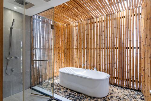 a bathroom with a tub and a bamboo wall at Maison Villa Nature Luxe in Ho Chi Minh City