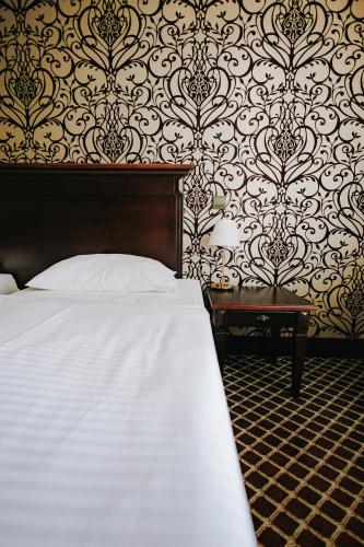 a bedroom with a bed and a table and wallpaper at Hotel Wileński in Olsztyn
