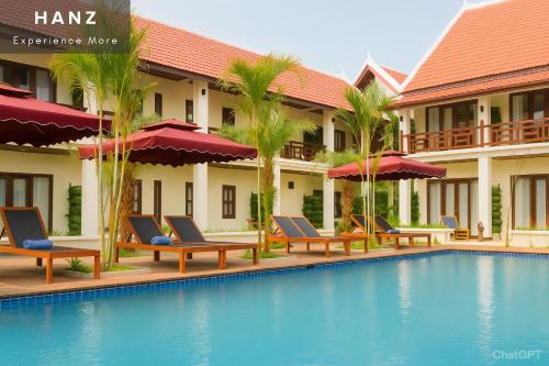 a hotel with a swimming pool with chairs and palm trees at Sunrise Hotel Luang Prabang Mekong river in Luang Prabang