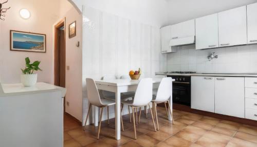 a kitchen with white cabinets and a table and chairs at Sperlonga Apartments - Villetta con discesa Mare in Sperlonga