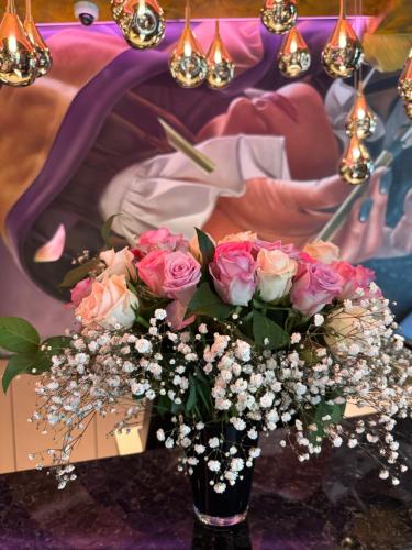 a vase filled with pink roses in front of a painting at Classic Hotel Harmonie in Cologne