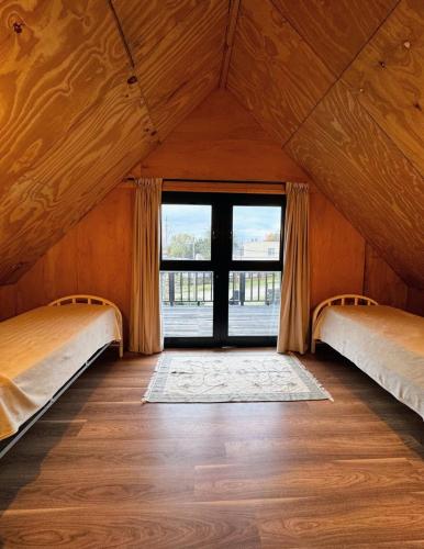 Dos camas en una habitación con una gran ventana. en Cabaña sustentable en Uribelarrea, en Uribelarrea