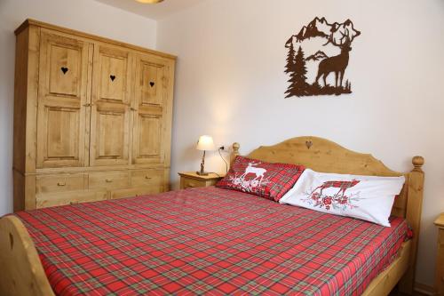 a bedroom with a bed with a red plaid blanket at Cuori, Cervi e Caprioli in Cesuna
