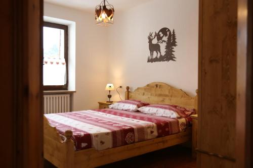 a bedroom with a bed with a red and white blanket at Cuori, Cervi e Caprioli in Cesuna