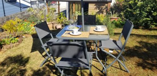 a table and chairs in a garden with a table and cups at Chez Gigi in Petite Île
