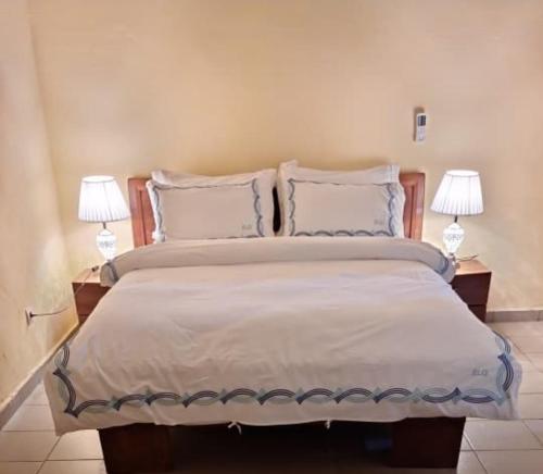 a bedroom with a large bed with two lamps at ELG Appart in Kribi