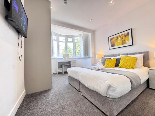 a bedroom with a large bed with yellow pillows at OX London Heathrow stay - 1 BUS to HEATHROW in New Bedfont