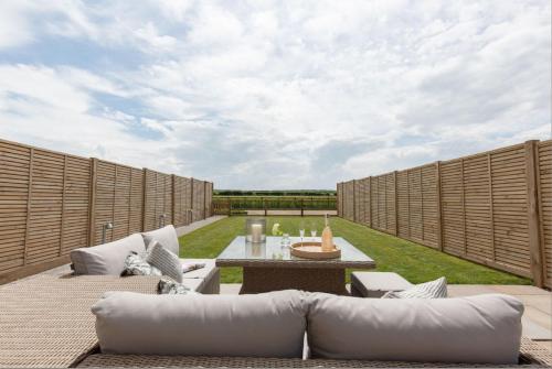 a patio with white couches and a table at No 1 The Hides Luxury House in North Norfolk in Titchwell