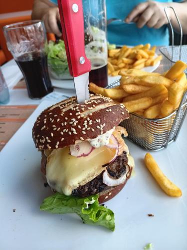 a knife cutting into a hamburger with french fries at Chez mamie in Sarralbe