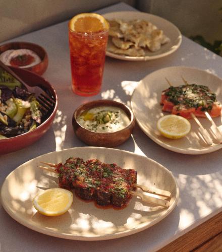 a table with plates of food and a drink at Hotel Erwin Venice Beach in Los Angeles
