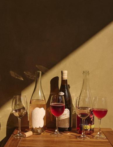 four wine bottles and wine glasses on a wooden table at Hotel Erwin Venice Beach in Los Angeles