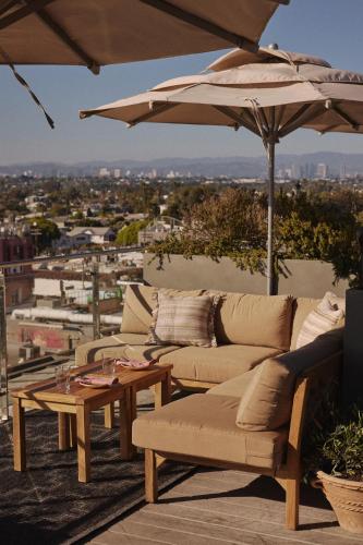 a patio with couches and a table and an umbrella at Hotel Erwin Venice Beach in Los Angeles